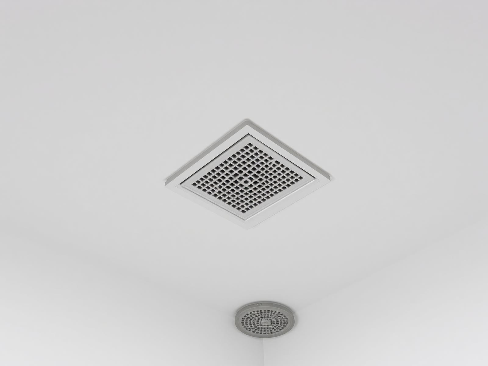Detail van een discrete vierkante plafondrooster in plaster plafond boven douche